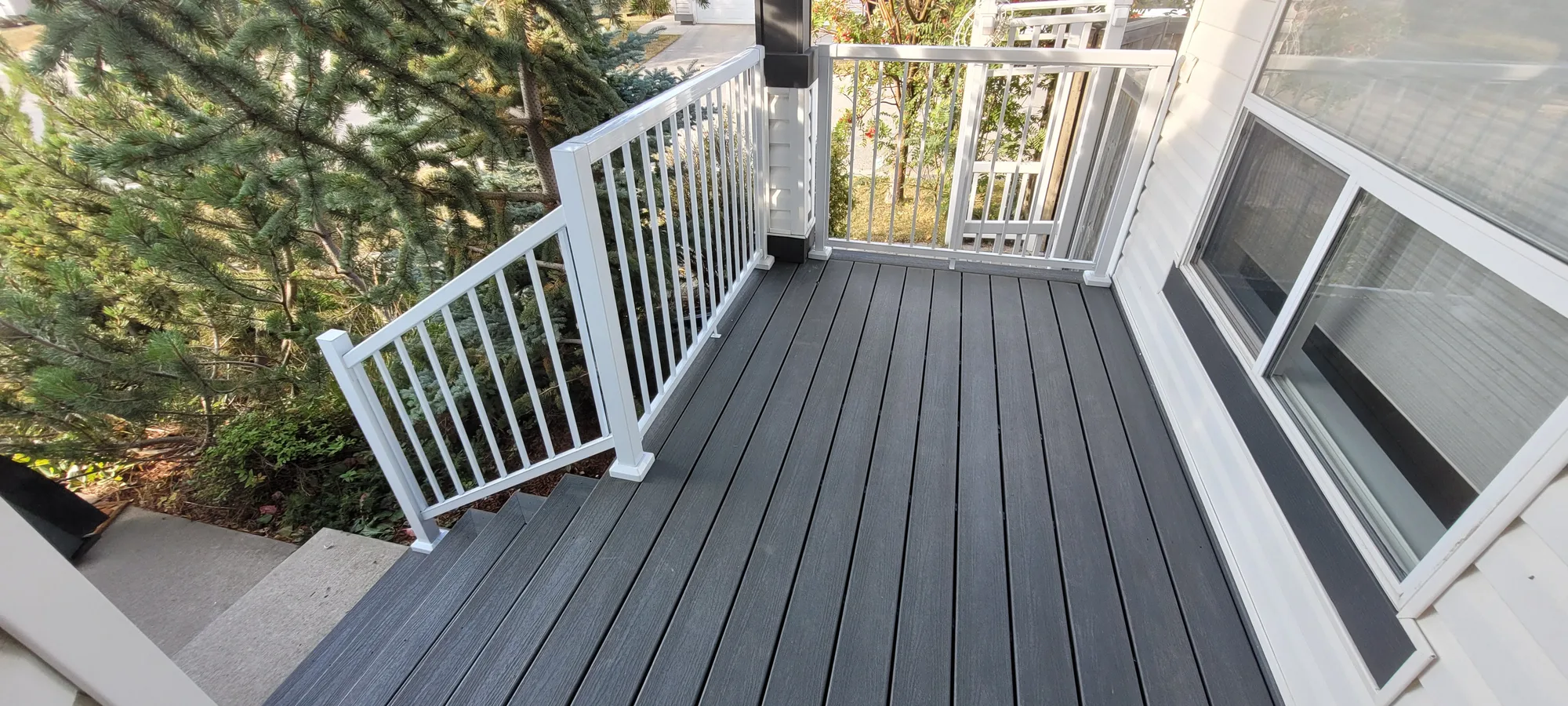 Dark composite deck with white railings beside a Calgary home.
