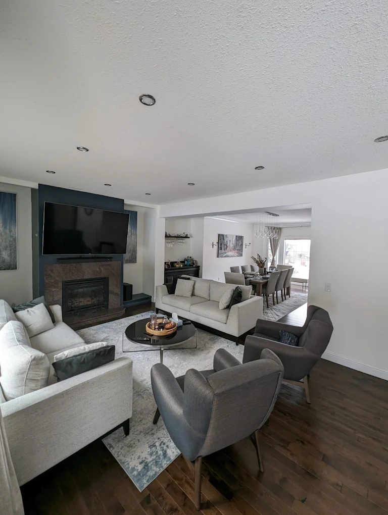 Open-concept living and dining room renovation with a fireplace, seating and warm wood floors.