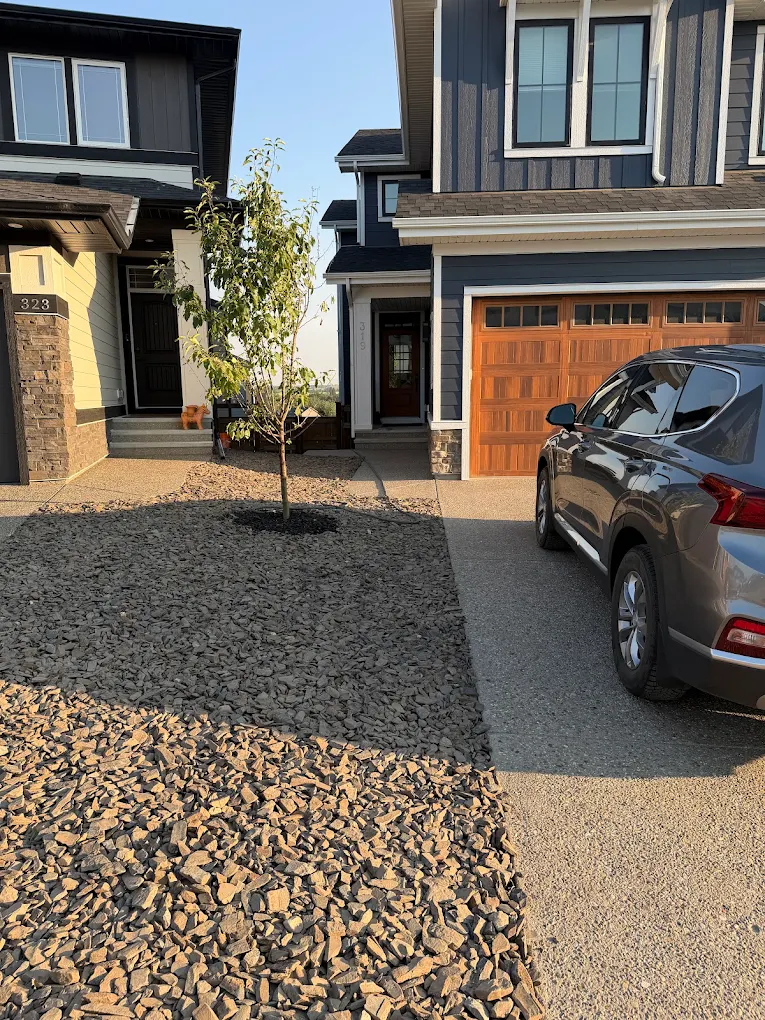 Finished Calgary-area residential front entry with landscaping, stone, siding and a wood garage door.